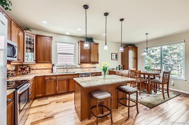 2872 Dreamcatcher Loop, Castle Rock, CO 80109 - kitchen with stainless steel appliances, light wood-style floors, decorative backsplash, brown cabinetry, and recessed lighting