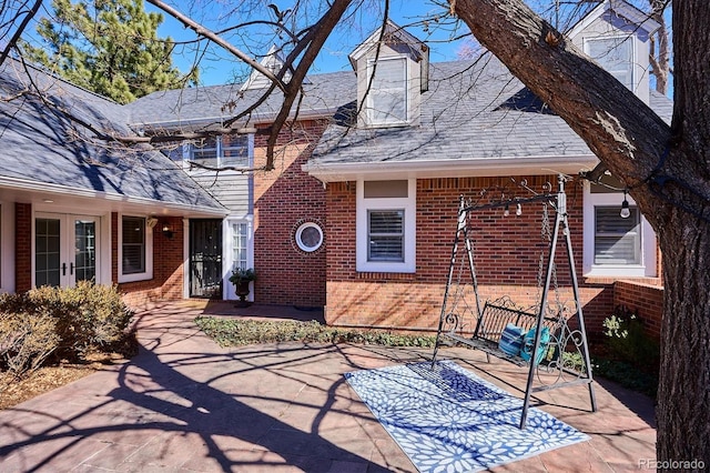 exterior space with brick siding, a patio area, and french doors