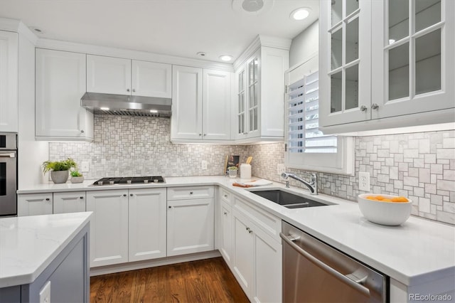 kitchen with under cabinet range hood, a sink, white cabinetry, appliances with stainless steel finishes, and dark wood-style floors