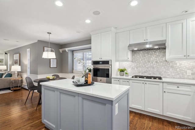 kitchen with white cabinets, dark wood-style flooring, a center island, stainless steel appliances, and under cabinet range hood