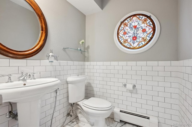 half bathroom featuring a baseboard radiator, toilet, a wainscoted wall, tile walls, and marble finish floor