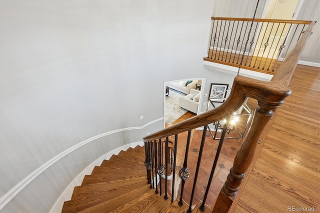 staircase featuring wood finished floors and baseboards