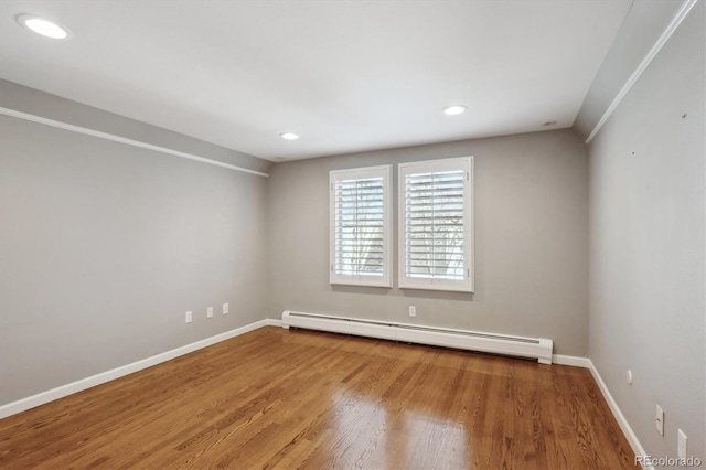 empty room with baseboards, a baseboard heating unit, wood finished floors, and recessed lighting