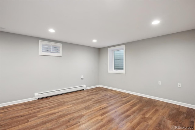 finished basement with a baseboard heating unit, wood finished floors, and baseboards