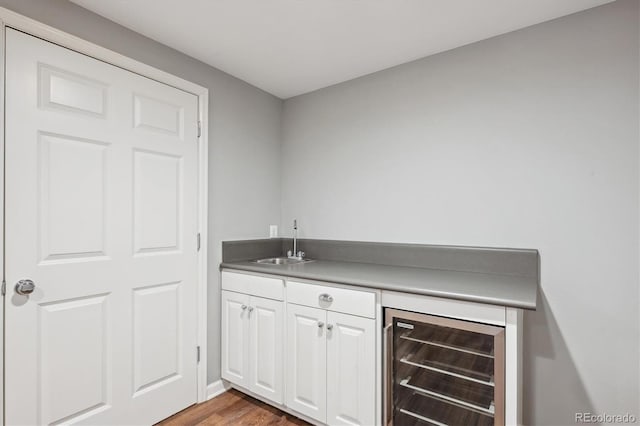 bar with beverage cooler, wet bar, a sink, and wood finished floors