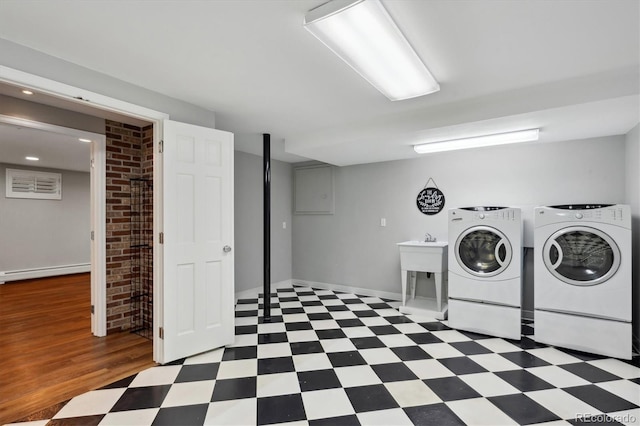 clothes washing area featuring a baseboard heating unit, tile patterned floors, and washer and dryer