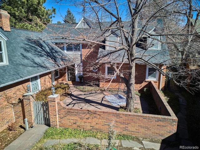 view of side of property featuring a gate, fence, and brick siding