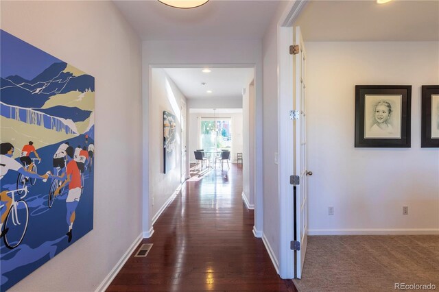 hall featuring baseboards, hardwood / wood-style floors, visible vents, and recessed lighting