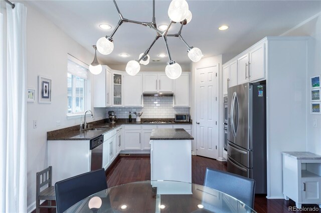 kitchen with a center island, a sink, white cabinets, backsplash, and appliances with stainless steel finishes