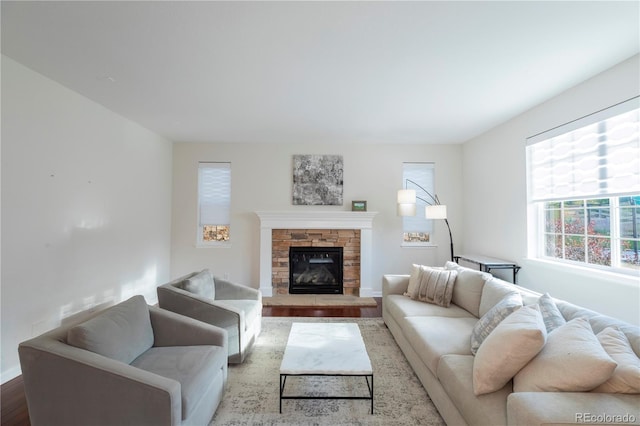 living room featuring baseboards, a stone fireplace, and wood finished floors