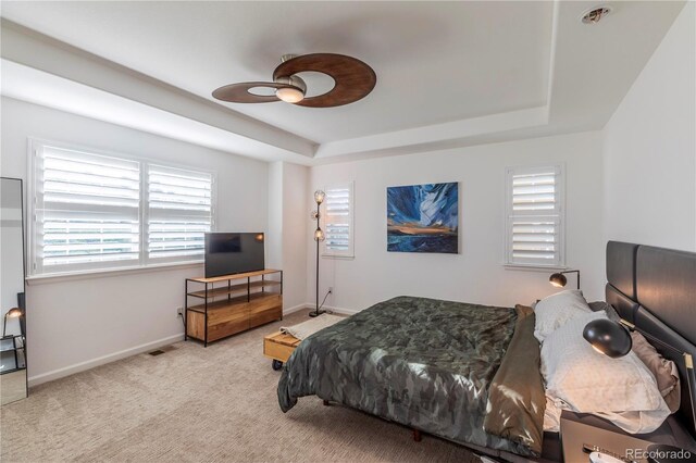 carpeted bedroom featuring a ceiling fan, visible vents, baseboards, and a raised ceiling