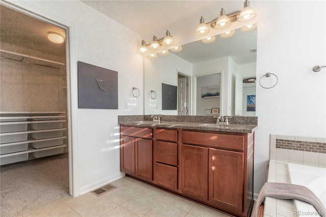 bathroom with a sink, visible vents, a tub, tile patterned flooring, and double vanity