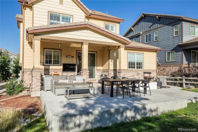 rear view of property featuring an outdoor hangout area, a patio, and stone siding