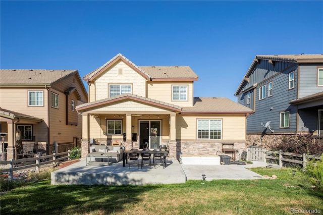 back of property with a fenced backyard, a patio, an outdoor living space, and stone siding