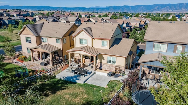back of house with a fenced backyard, a patio area, stone siding, and a residential view