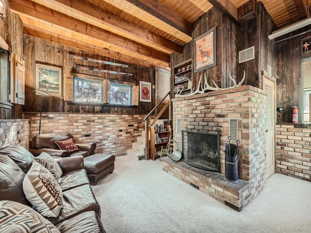 carpeted living room featuring wood walls, a brick fireplace, wooden ceiling, beamed ceiling, and brick wall