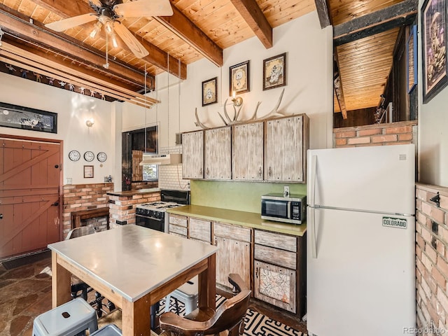 kitchen with gas stove, wooden ceiling, beamed ceiling, brick wall, and white refrigerator