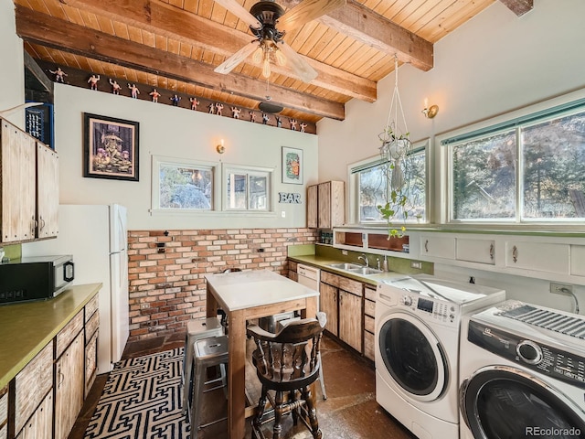 laundry area featuring wooden ceiling, brick wall, sink, washing machine and clothes dryer, and ceiling fan