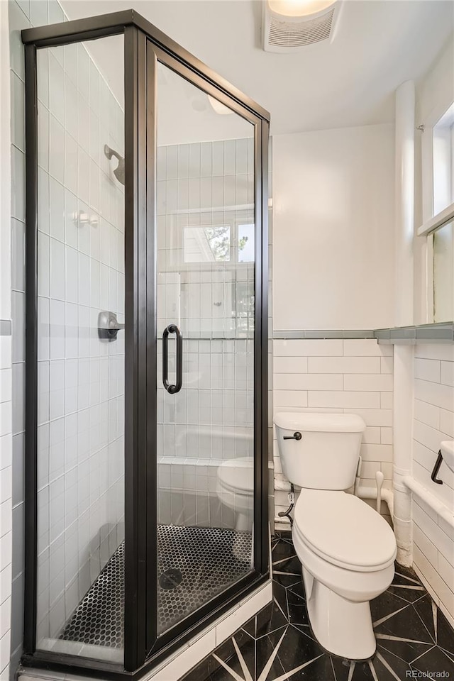 bathroom with toilet, walk in shower, and tile walls