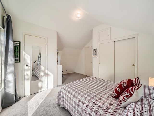 bedroom featuring a closet, vaulted ceiling, and light colored carpet