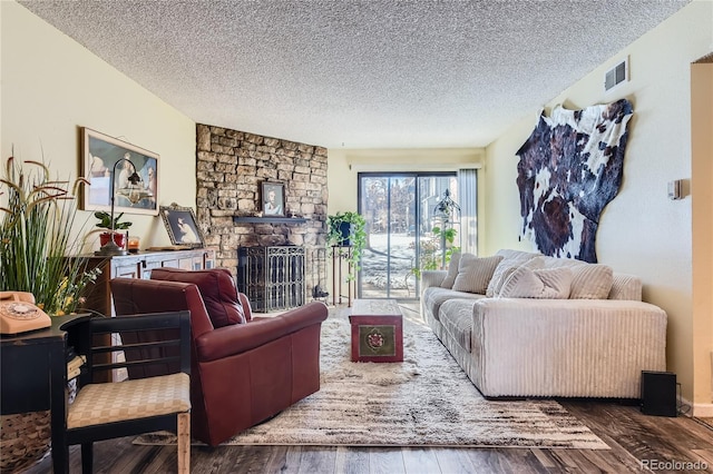 living room with a fireplace, a textured ceiling, and dark wood-type flooring