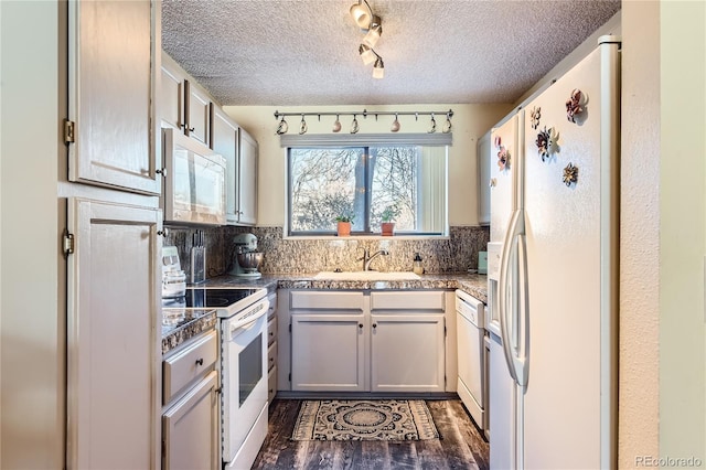 kitchen featuring tasteful backsplash, sink, dark wood-type flooring, and white appliances