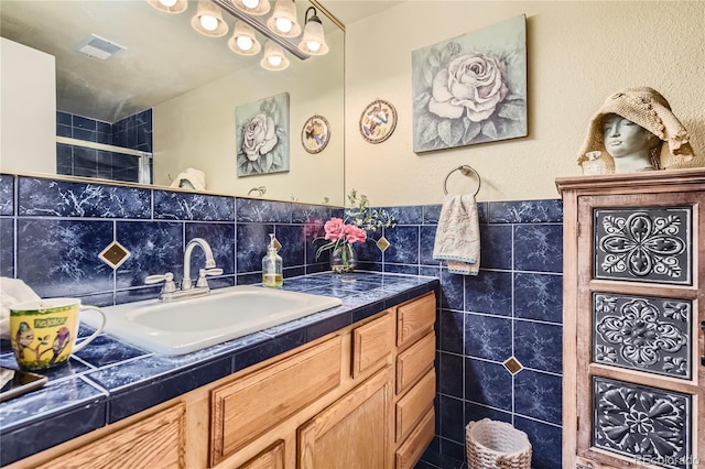 bathroom with vanity, a shower, and tile walls