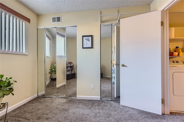 unfurnished bedroom featuring carpet, a textured ceiling, and washer / clothes dryer