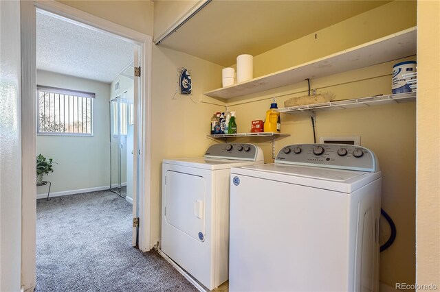 laundry room with a textured ceiling, light colored carpet, and washing machine and clothes dryer