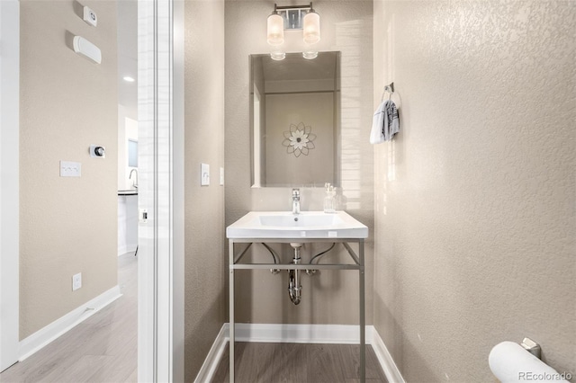1928 W 67th Pl, Denver, CO 80221 - half bath with wood finished floors, a textured wall, baseboards, and a sink