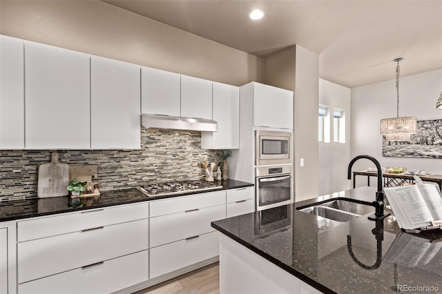 1928 W 67th Pl, Denver, CO 80221 - kitchen featuring stainless steel appliances, tasteful backsplash, dark stone counters, white cabinets, and under cabinet range hood