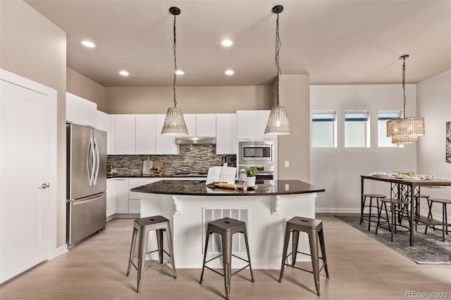 1928 W 67th Pl, Denver, CO 80221 - kitchen featuring stainless steel appliances, under cabinet range hood, a breakfast bar, dark countertops, and recessed lighting