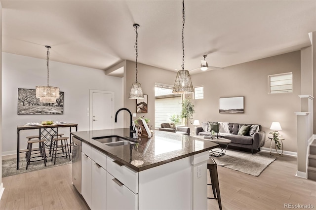 1928 W 67th Pl, Denver, CO 80221 - kitchen with light wood-style floors, white cabinets, dishwasher, a center island with sink, and decorative light fixtures
