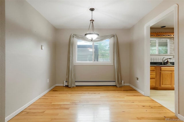 8595 S Yarrow St, Littleton, CO 80128 - unfurnished dining area with a baseboard radiator, healthy amount of natural light, and light wood finished floors