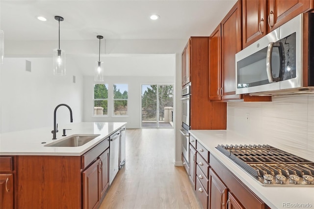 kitchen featuring stainless steel appliances, light wood finished floors, a sink, and light countertops