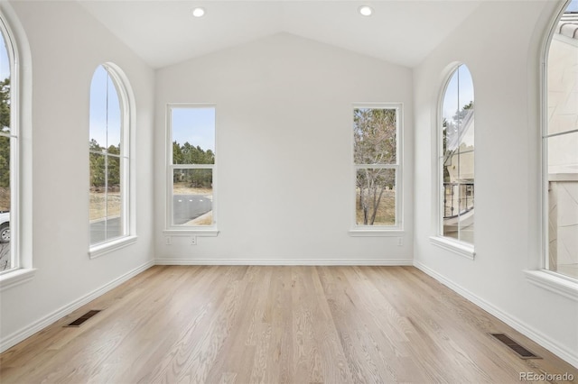 interior space featuring light wood finished floors, baseboards, visible vents, and vaulted ceiling