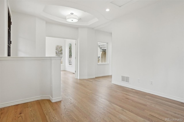 unfurnished room featuring baseboards, visible vents, a tray ceiling, light wood-style floors, and recessed lighting