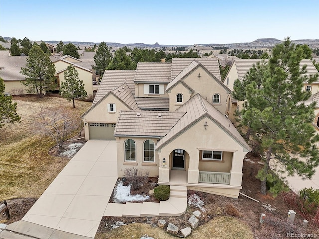 view of front of property featuring driveway, a tiled roof, an attached garage, and stucco siding