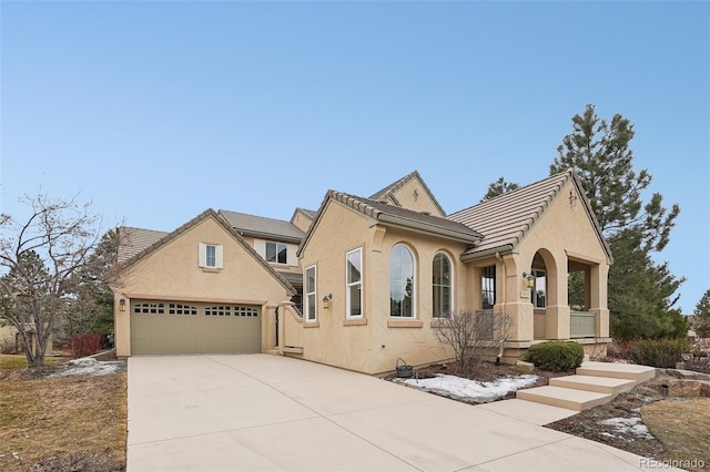 view of front of property with driveway, a tile roof, a garage, and stucco siding