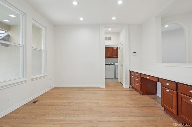 interior space with light wood finished floors, washing machine and dryer, visible vents, and built in study area