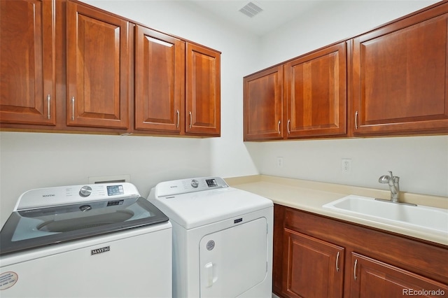 laundry area featuring a sink, cabinet space, washing machine and clothes dryer, and visible vents