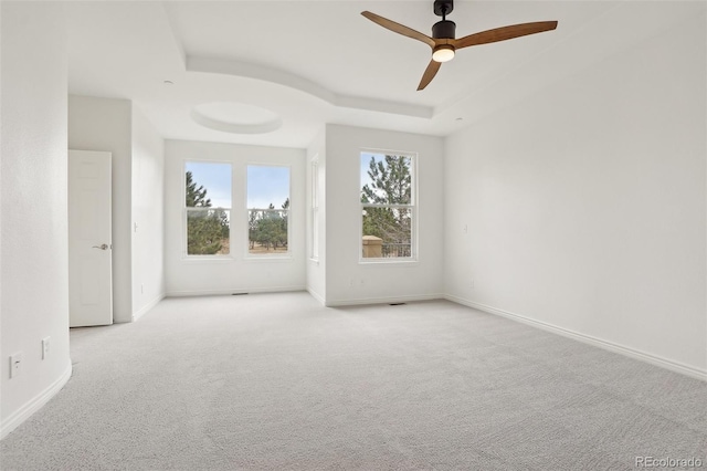 spare room featuring carpet floors, visible vents, a ceiling fan, baseboards, and a raised ceiling