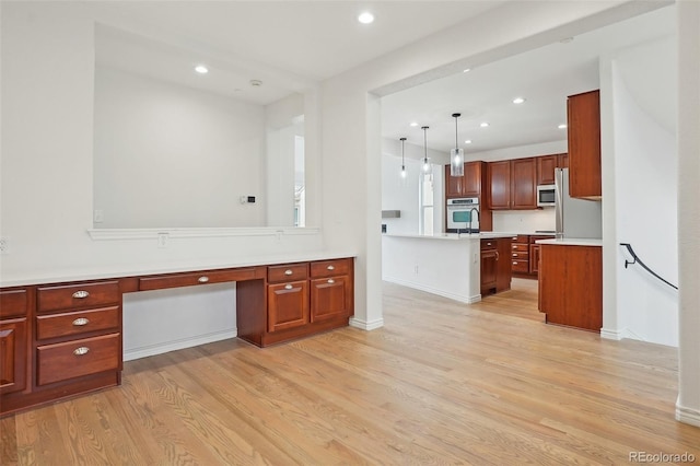 kitchen featuring recessed lighting, stainless steel appliances, light countertops, light wood-type flooring, and built in study area