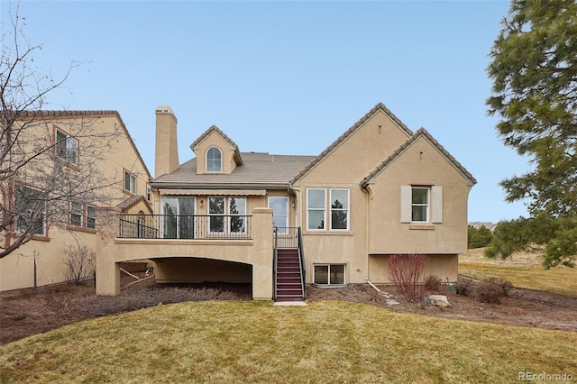 rear view of house with a yard, a chimney, stucco siding, stairway, and a wooden deck