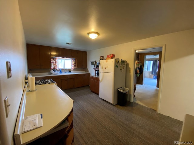 12729 Desert Dr, Sterling, CO 80751 - kitchen featuring freestanding refrigerator, dark carpet, light countertops, stovetop, and brown cabinets