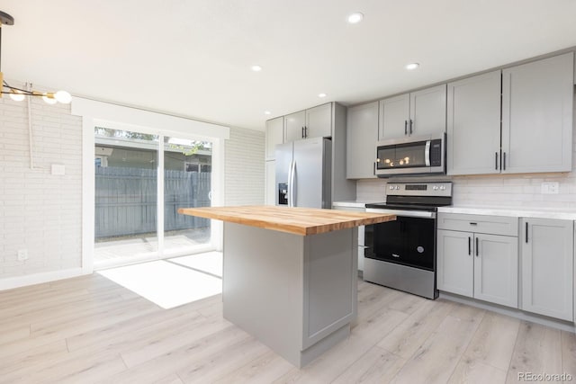 kitchen with stainless steel appliances, wooden counters, light hardwood / wood-style flooring, and gray cabinetry