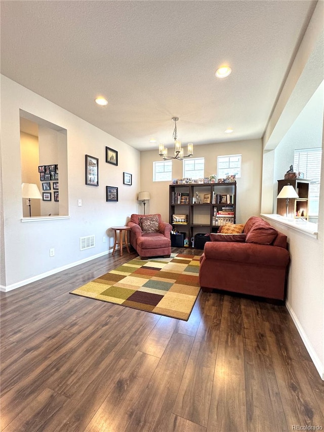 living room with a textured ceiling, dark hardwood / wood-style flooring, and a notable chandelier