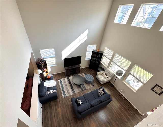 living room with a high ceiling, dark hardwood / wood-style flooring, and a wealth of natural light