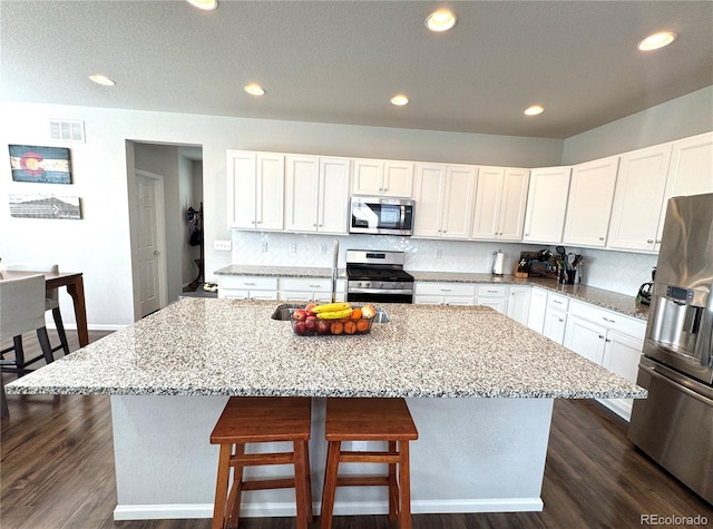 kitchen featuring dark hardwood / wood-style floors, light stone countertops, a center island, and stainless steel appliances