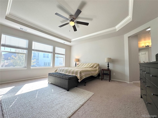 carpeted bedroom with ceiling fan, a raised ceiling, crown molding, and multiple windows